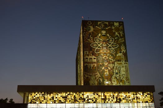 Dusk view of the Biblioteca Central's vibrant mural in Mexico City's UNAM campus.
