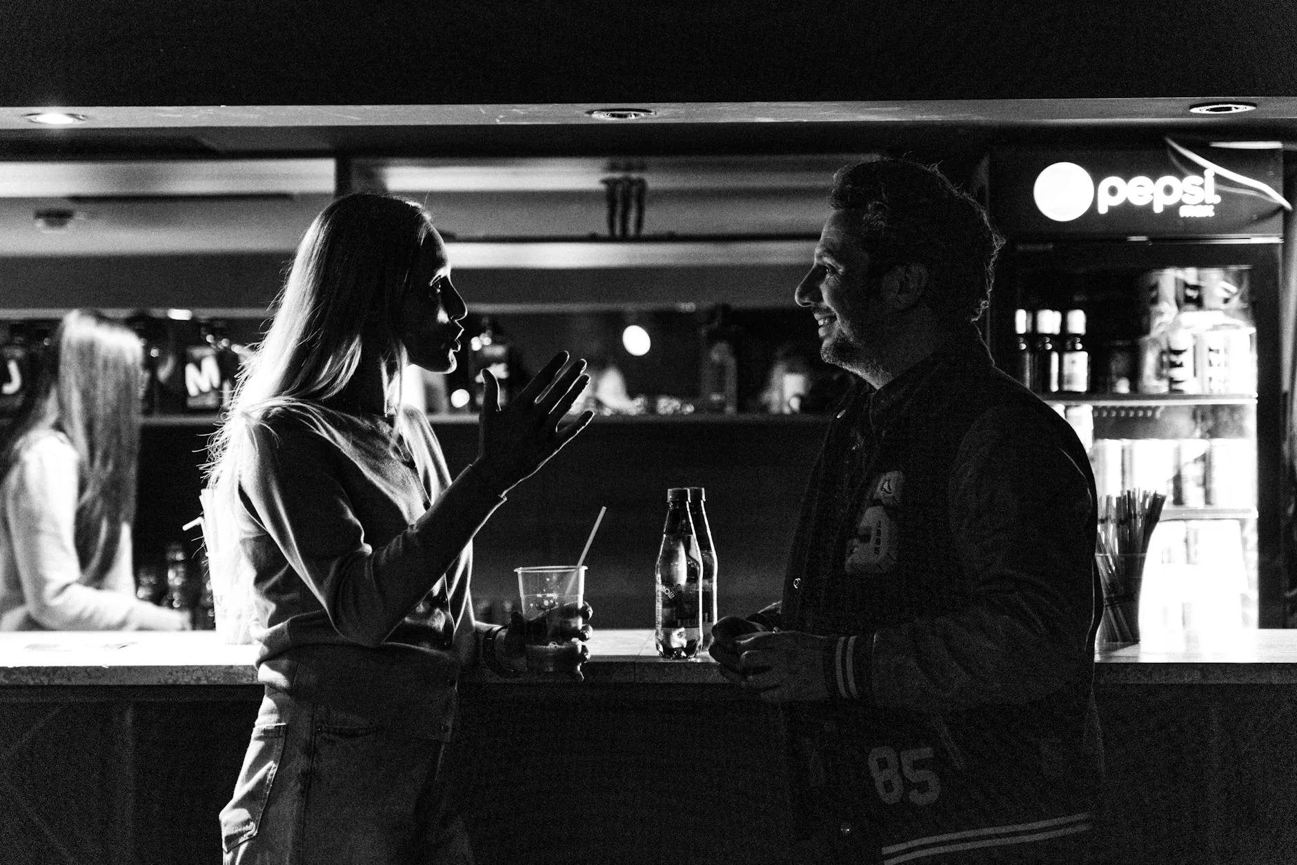Hombre y mujer conversando casualmente en un bar con confianza natural.