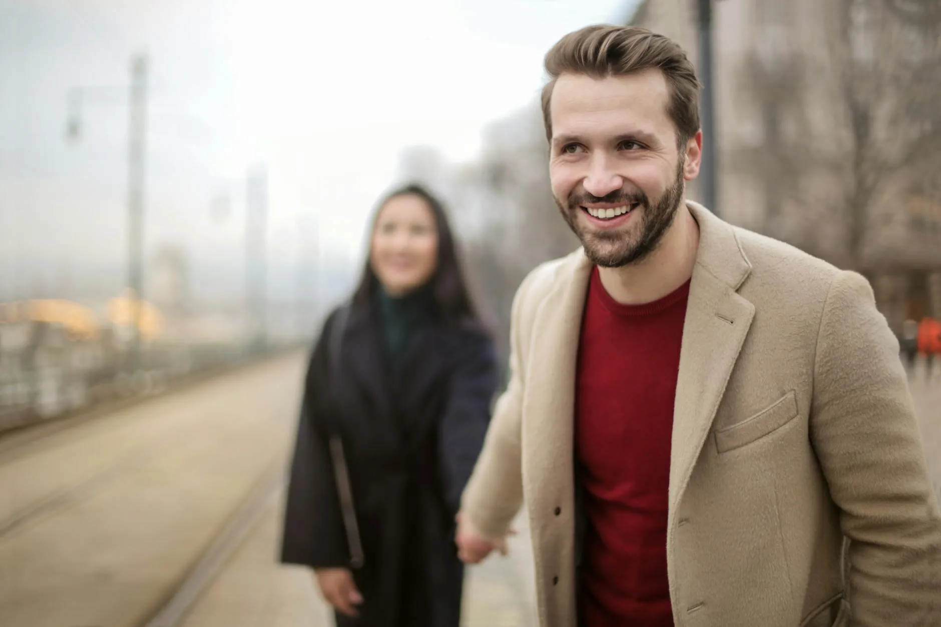 Hombre acercándose a una mujer con una sonrisa confiada y natural en la calle.
