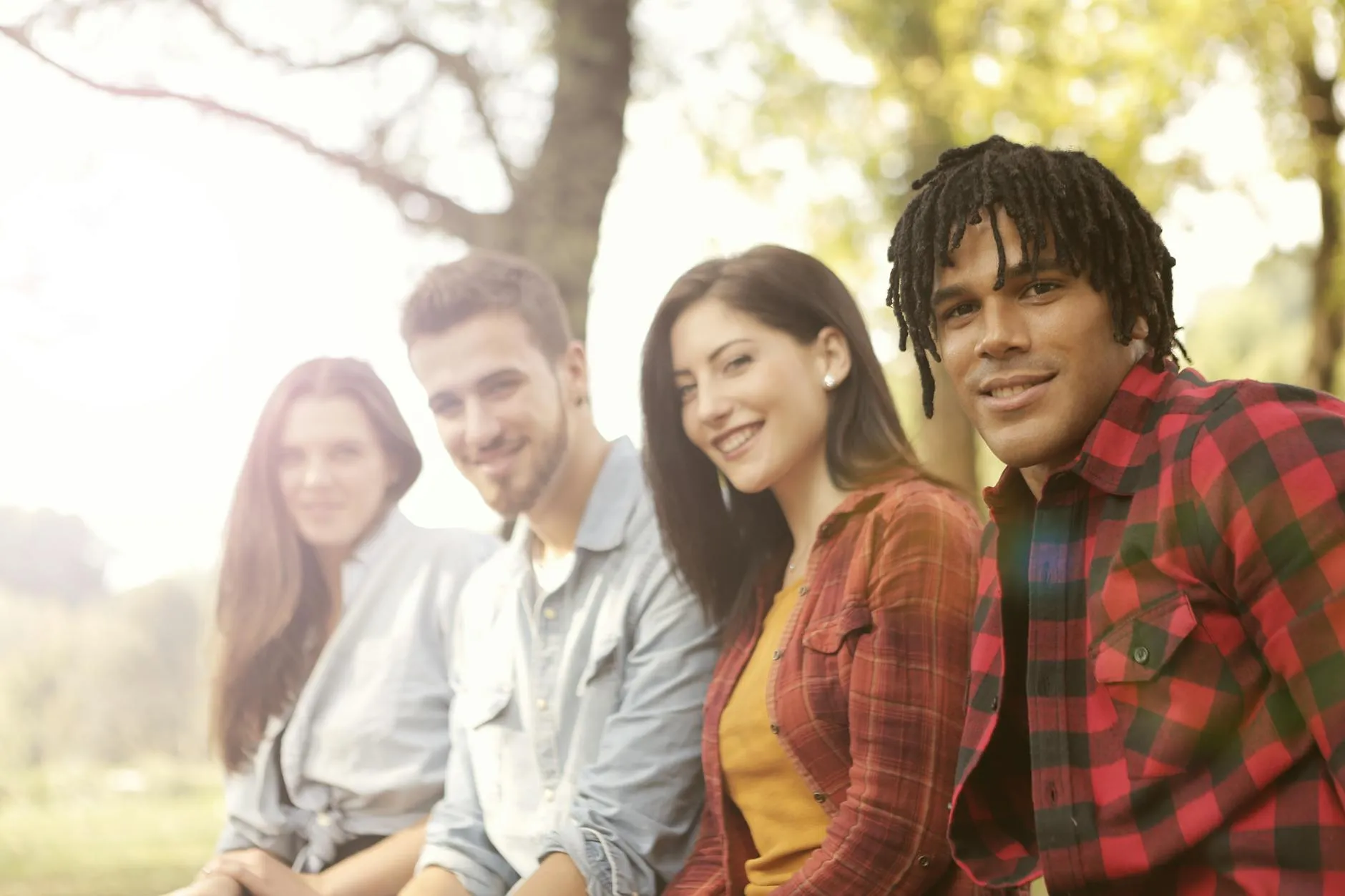 Grupo diverso de amigos socializando y riendo juntos en un ambiente natural.