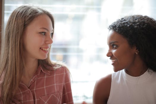 Two women enjoying a friendly indoor conversation, capturing togetherness and happiness.