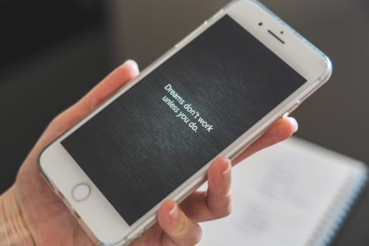 Close-up of hand holding smartphone with motivational quote 'Dreams don't work unless you do.'