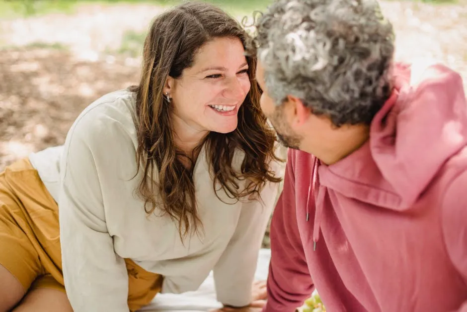 Smiling couple bonding during a sunny outdoor picnic, enjoying nature and each other's company.