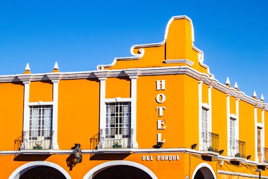 Exterior of aged historical building with bright yellow walls and symmetric balconies against blue sky